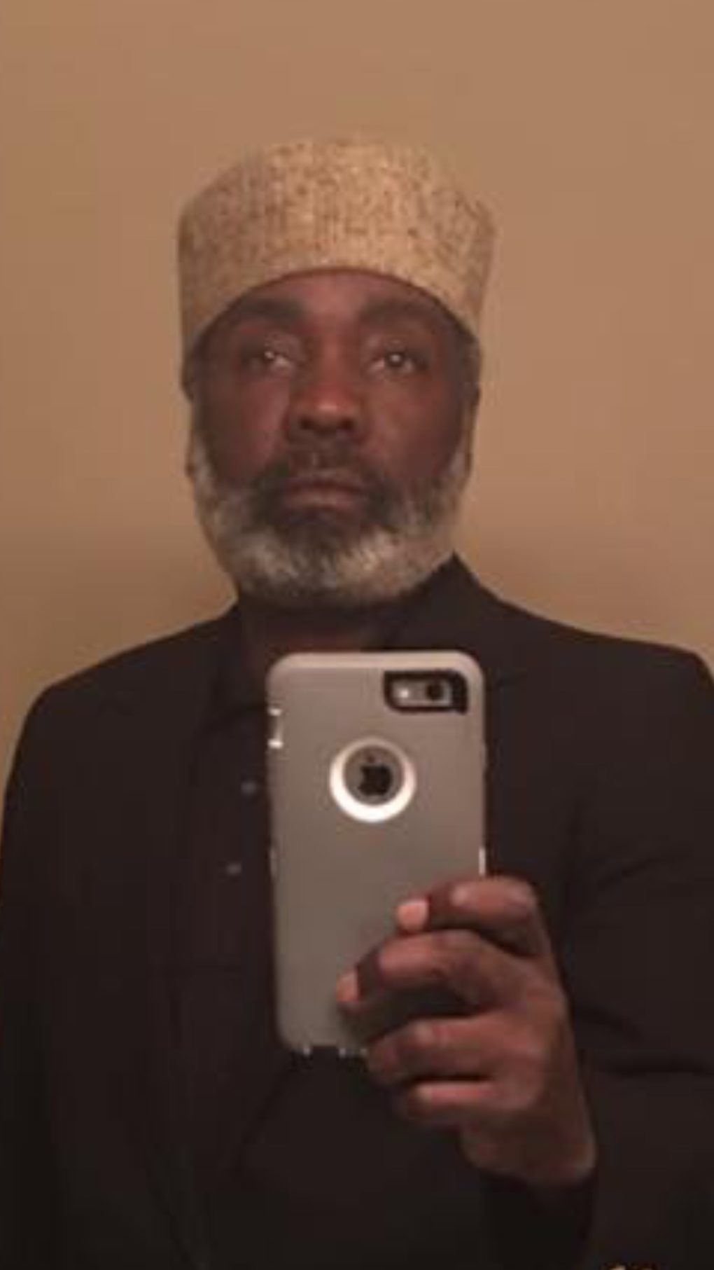 Man with beard and hat looking at camera.